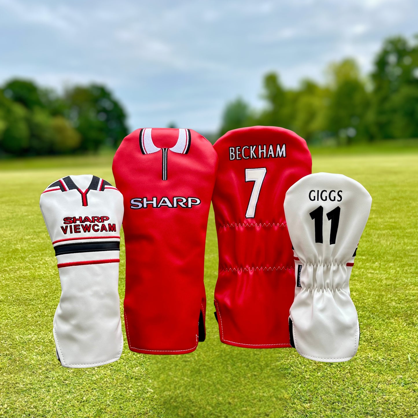 Four golf club heads with covers featuring sports team branding on a grassy background.