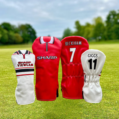 Four golf club heads with covers featuring sports team branding on a grassy background.